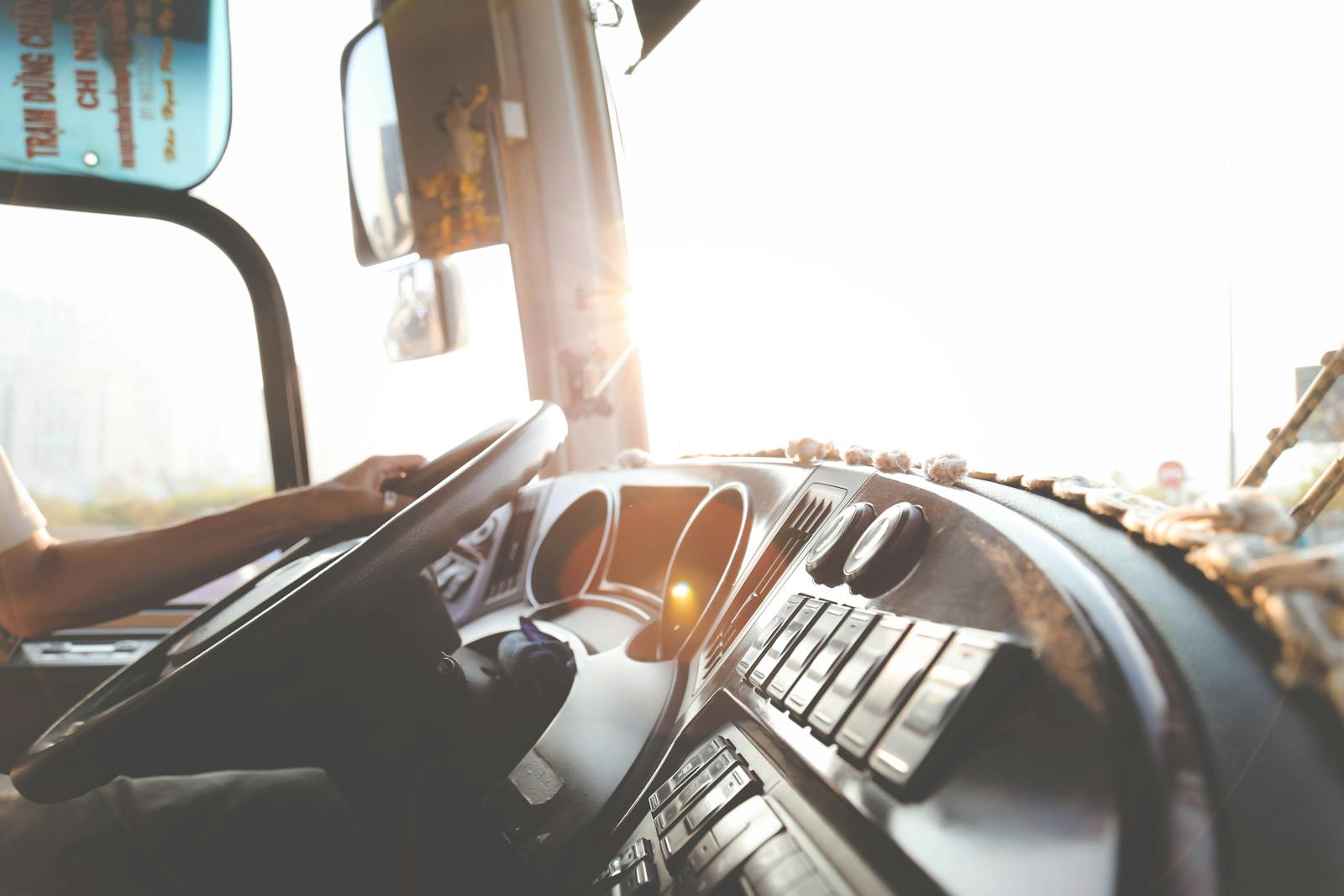A bus driver navigating the city streets during a sunny day, focusing on the road. non-truck liability and bobtail